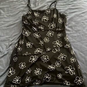 Black mini dress with white flowers, ruffle seem edges, has ruffle seem patterns